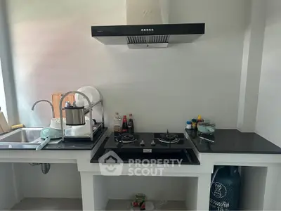 Modern kitchen with gas stove and sleek ventilation hood, featuring a compact and efficient layout.