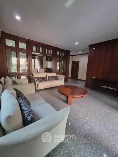 Spacious living room with elegant wood paneling and cozy sofas, perfect for relaxation.