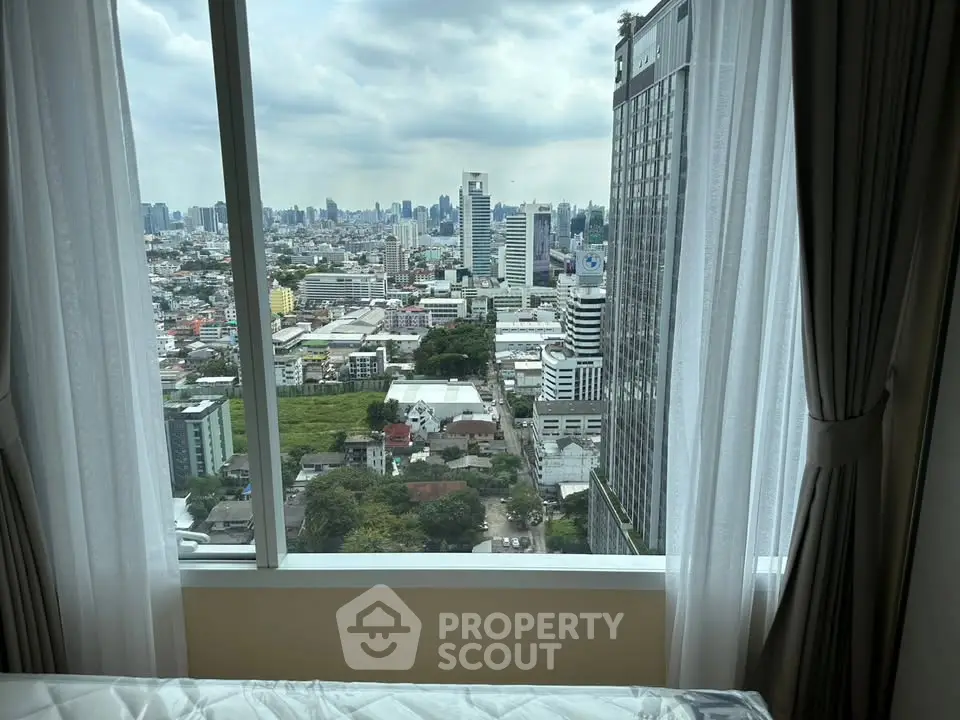 Stunning cityscape view from high-rise apartment window with modern curtains.