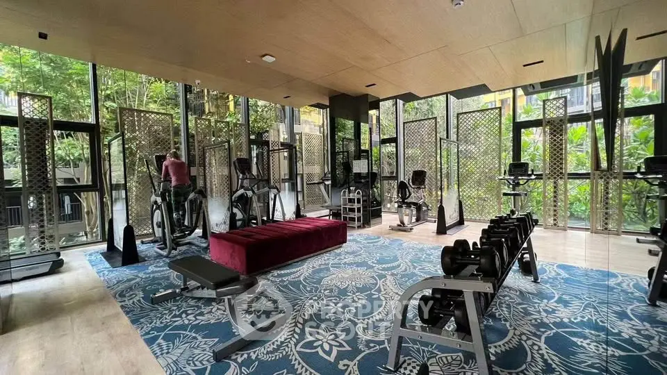 Luxurious gym with modern equipment and lush garden views in upscale residential building.