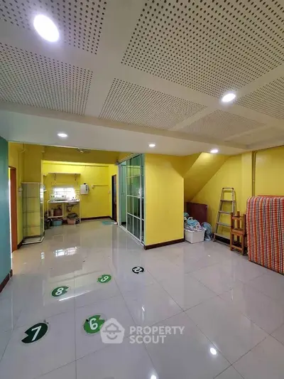 Spacious interior with vibrant yellow walls and modern lighting, ideal for creative workspace or cozy living area.