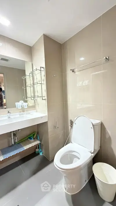 Modern bathroom with sleek fixtures and neutral tiles, featuring a spacious vanity and contemporary toilet.