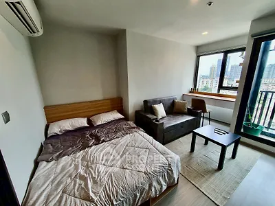 Modern studio apartment with city view, cozy bed, and stylish sofa.
