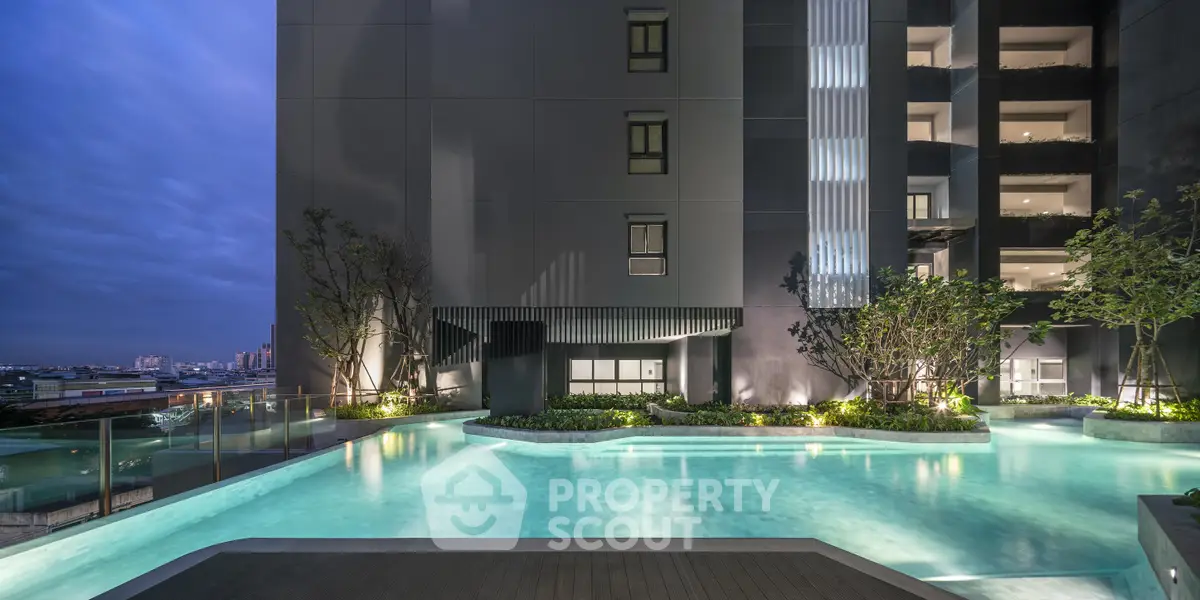 Luxurious modern building with illuminated pool and stunning city view at dusk.