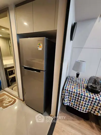 Modern kitchen corner with sleek fridge and colorful tablecloth, perfect for compact living spaces.