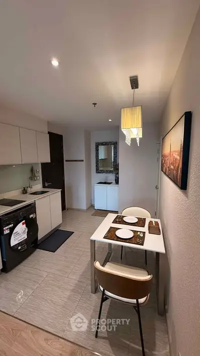 Modern kitchen with dining area featuring sleek cabinetry and stylish lighting in a cozy apartment.