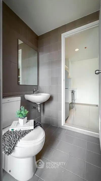 Modern bathroom with sleek design and view into adjacent kitchen area.