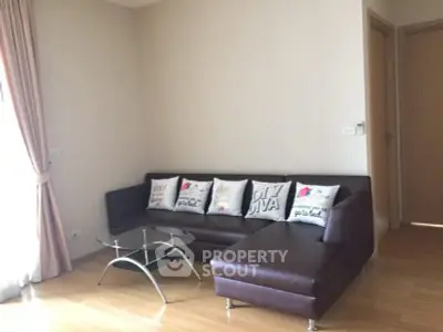 Spacious living room with modern brown leather sofa and glass coffee table, perfect for relaxation.