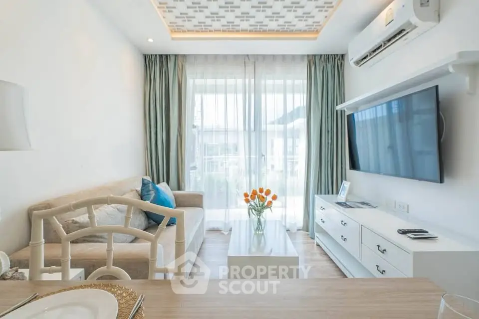 Modern living room with stylish decor, large TV, and natural light from floor-to-ceiling windows.