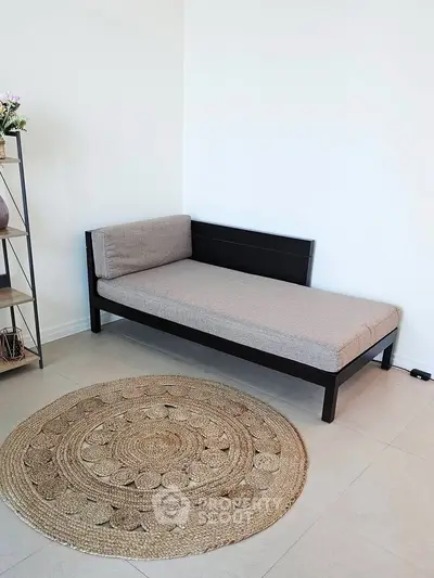Minimalist living room with modern daybed and woven rug, perfect for cozy relaxation.