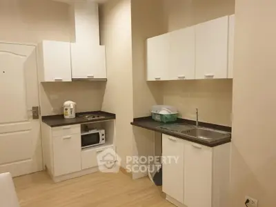 Modern compact kitchen with sleek white cabinets and appliances