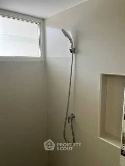 Modern bathroom with sleek shower design and natural light window.
