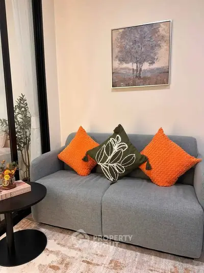 Cozy living room with modern gray sofa and vibrant orange cushions, perfect for relaxation.