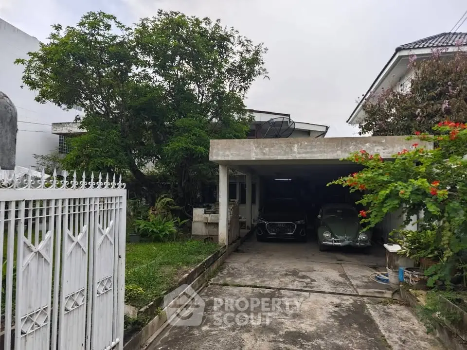 Charming suburban home with spacious driveway and lush greenery, featuring a classic carport.