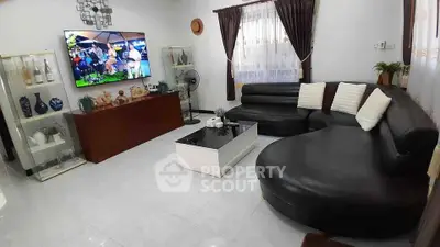 Spacious living room with modern black leather sectional sofa and wall-mounted TV, perfect for relaxation.