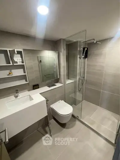 Modern bathroom with sleek fixtures and glass shower enclosure in contemporary apartment.