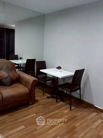 Cozy living room with elegant seating and dining area, featuring a stylish brown sofa and modern decor.