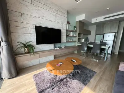 Modern living room with stylish decor and open kitchen layout, featuring a wall-mounted TV and cozy dining area.