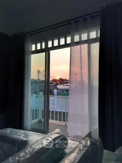 Serene bedroom with a stunning sunset view through large glass doors leading to a spacious balcony, perfect for unwinding.