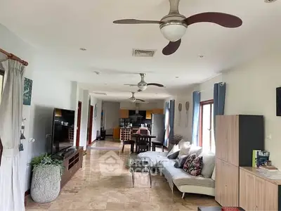 Spacious open-plan living room with modern decor and ceiling fans