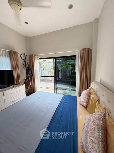 Spacious bedroom with sliding glass doors leading to a private garden patio.