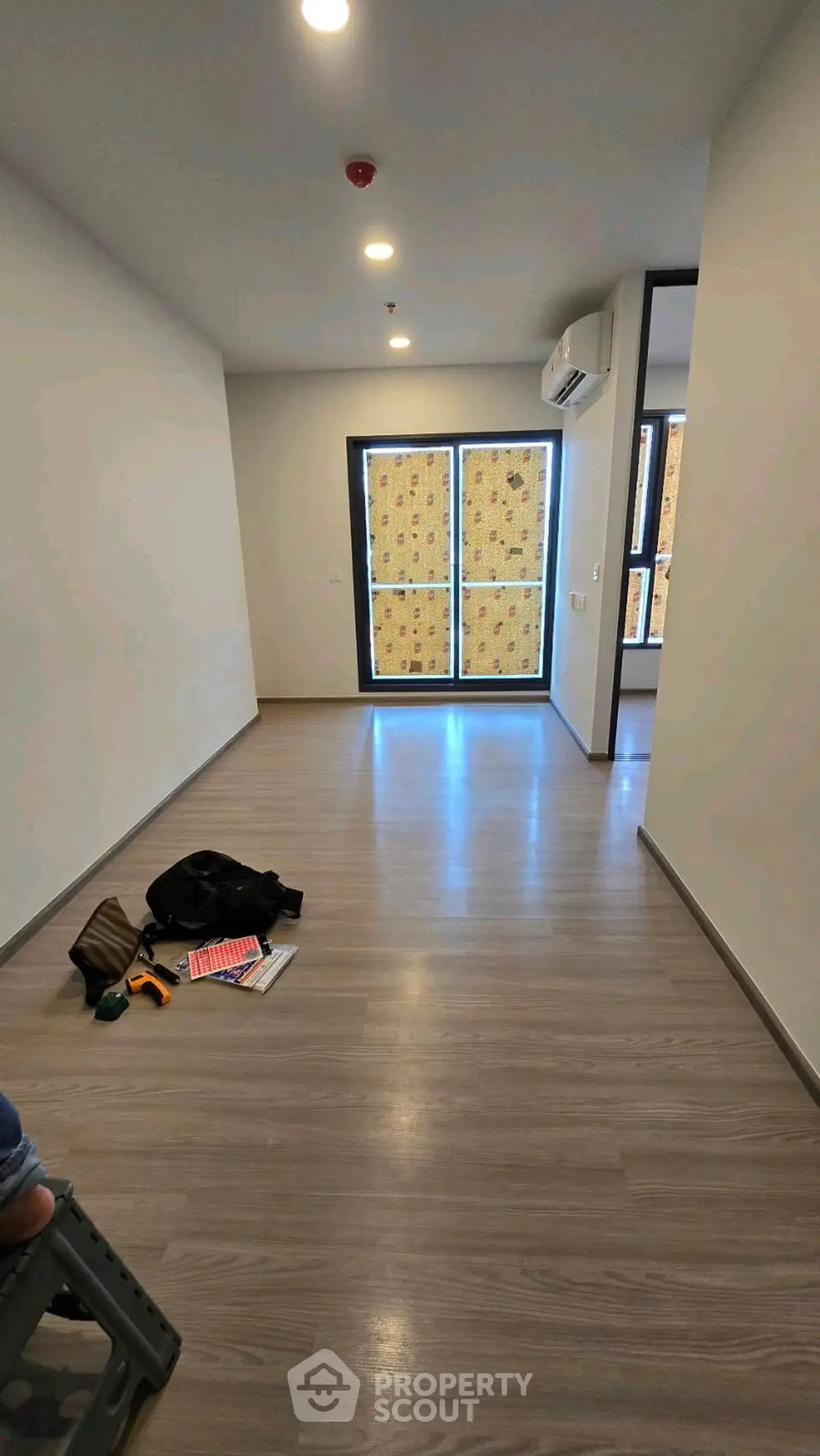 Spacious modern living room with wooden flooring and large windows, perfect for natural light.