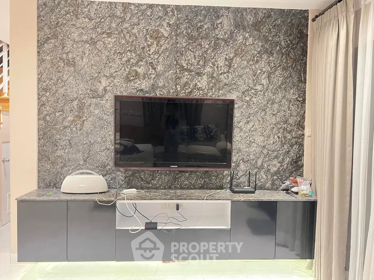 Modern living room with sleek TV setup and elegant stone accent wall