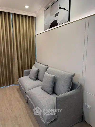 Modern living room with stylish gray sofa and elegant wall art, featuring floor-to-ceiling curtains.