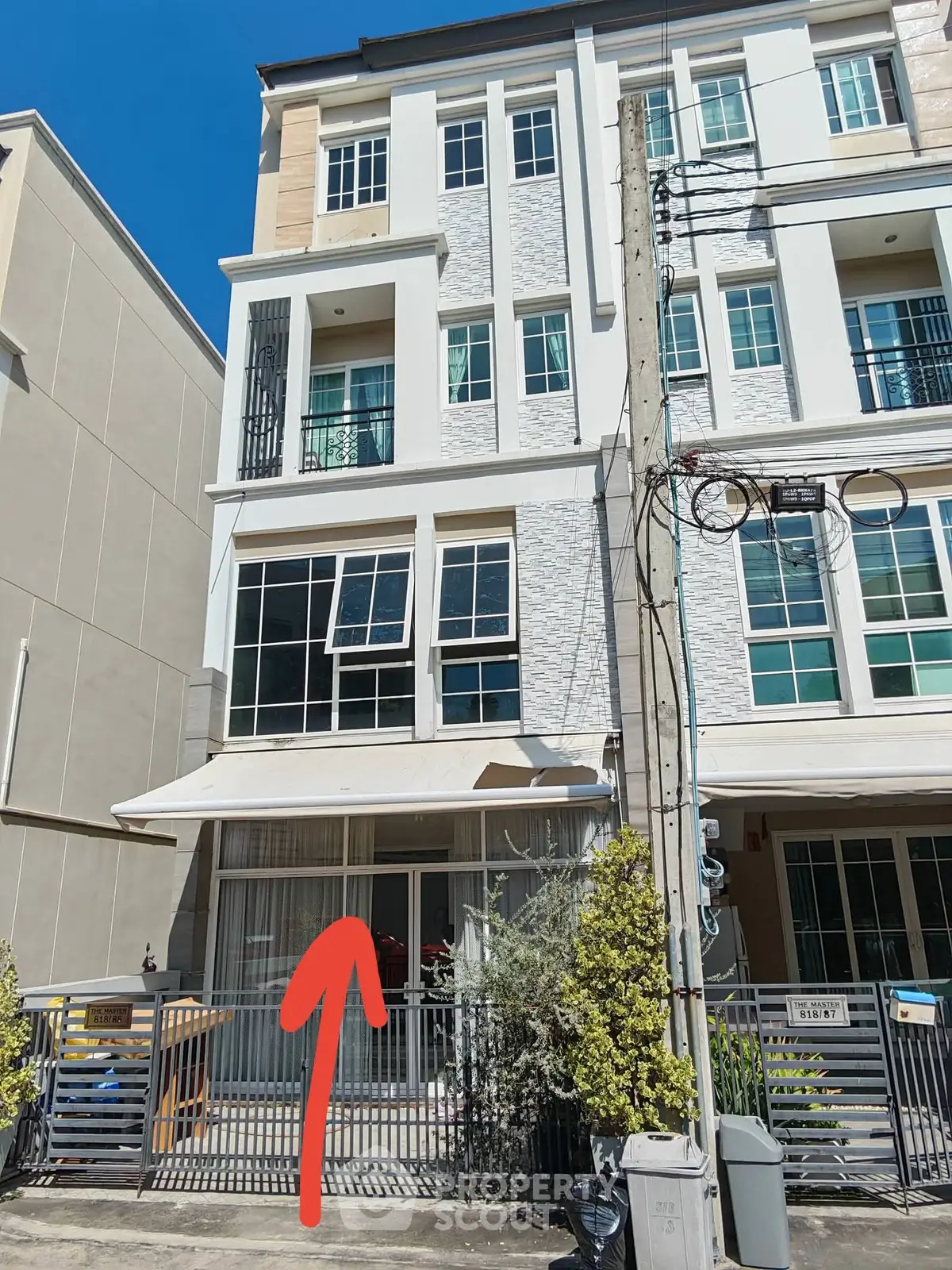 Modern multi-story townhouse exterior with large windows and gated entrance.