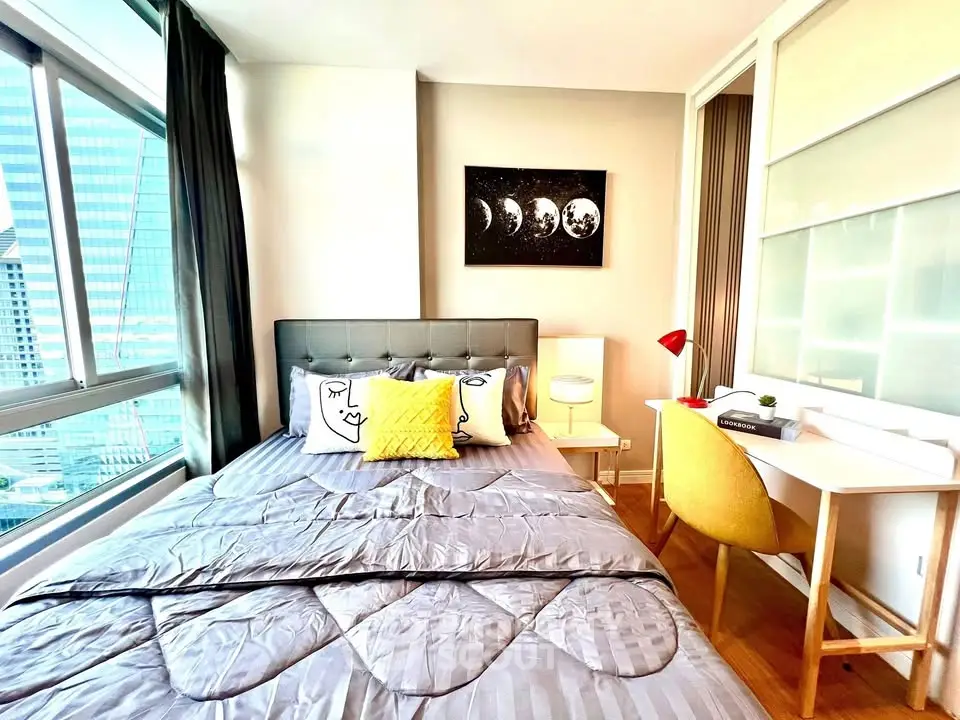Modern bedroom with city view, stylish decor, and cozy workspace in a high-rise apartment.
