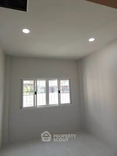 Bright empty room with large window and recessed lighting, perfect for customization.