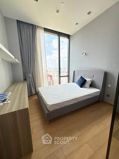 Modern bedroom with large window offering stunning city views, featuring sleek wooden flooring and minimalist decor.
