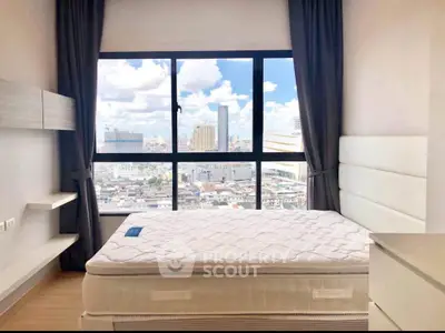 Modern bedroom with large window offering stunning city view in high-rise apartment.