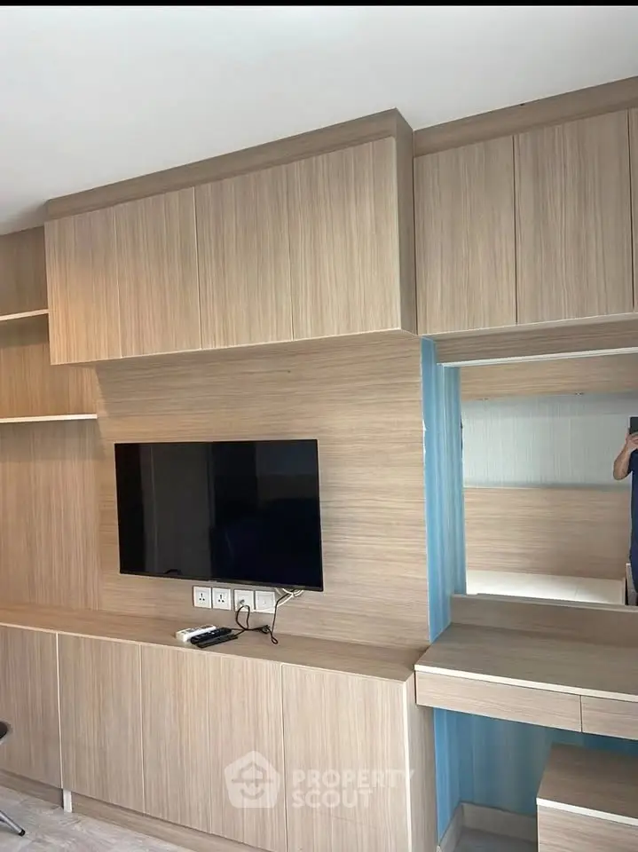 Modern living room with sleek wooden cabinetry and mounted flat-screen TV