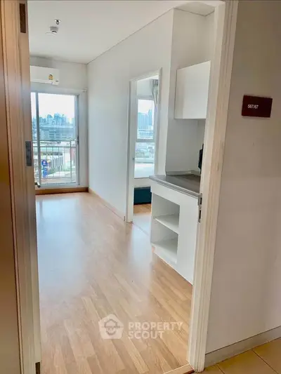 Bright apartment interior with wooden flooring and city view balcony.