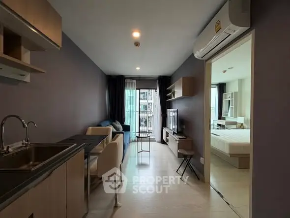 Modern apartment with open living and kitchen area, featuring sleek design and natural light.
