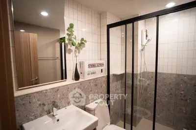 Modern bathroom with sleek shower enclosure and stylish sink in a contemporary apartment.