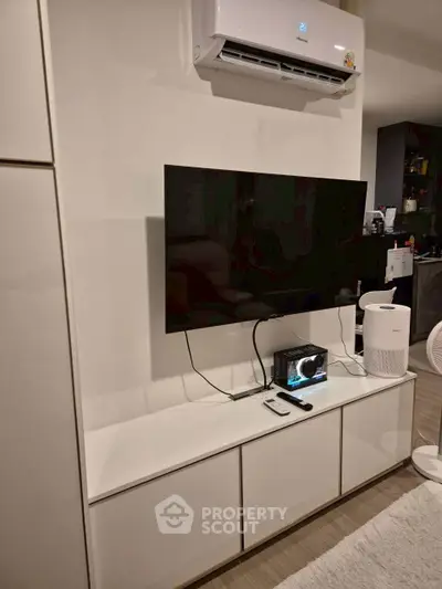 Modern living room with wall-mounted TV and sleek white cabinetry