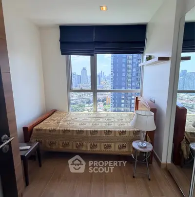 Cozy bedroom with city view, featuring a single bed and stylish decor in a modern high-rise apartment.