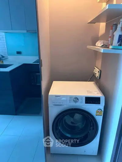 Compact laundry area with modern washing machine in sleek apartment kitchen.