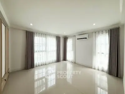 Spacious and bright empty living room with large windows and modern air conditioning unit.