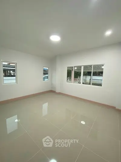 Spacious empty room with large windows and glossy tiled floor