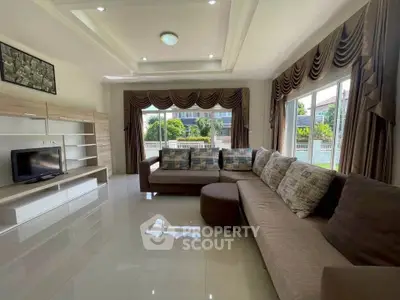Spacious living room with modern decor and large windows offering garden views.