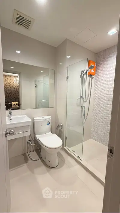 Modern bathroom with glass shower and sleek fixtures in a contemporary apartment.