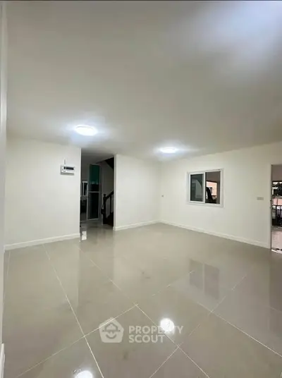 Spacious empty living room with glossy tiled floors and bright lighting