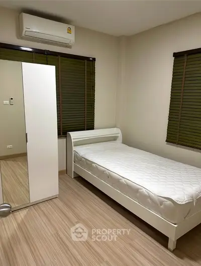 Cozy bedroom with single bed, wardrobe, and air conditioning in modern apartment.