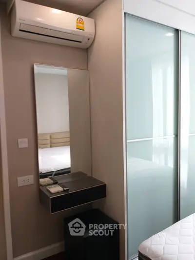 Modern bedroom with sleek sliding closet doors and air conditioning unit.