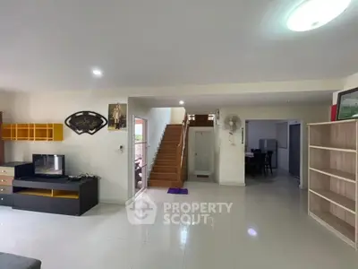 Spacious open-plan living area with modern staircase and sleek tile flooring