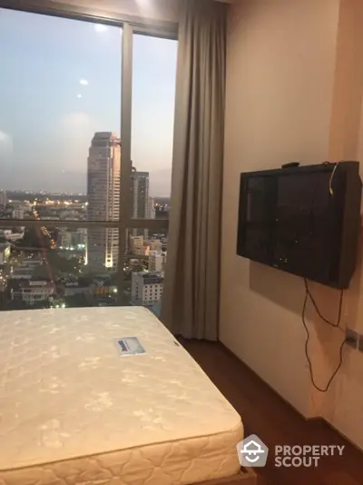 Modern bedroom with city view and wall-mounted TV in high-rise apartment