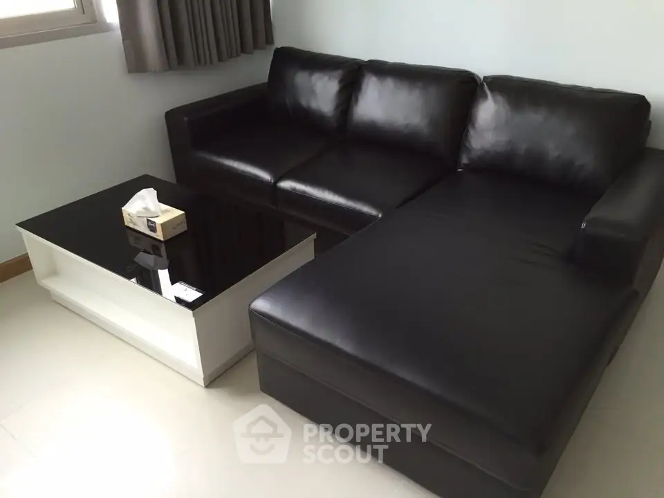Modern living room with sleek black leather sofa and stylish coffee table.